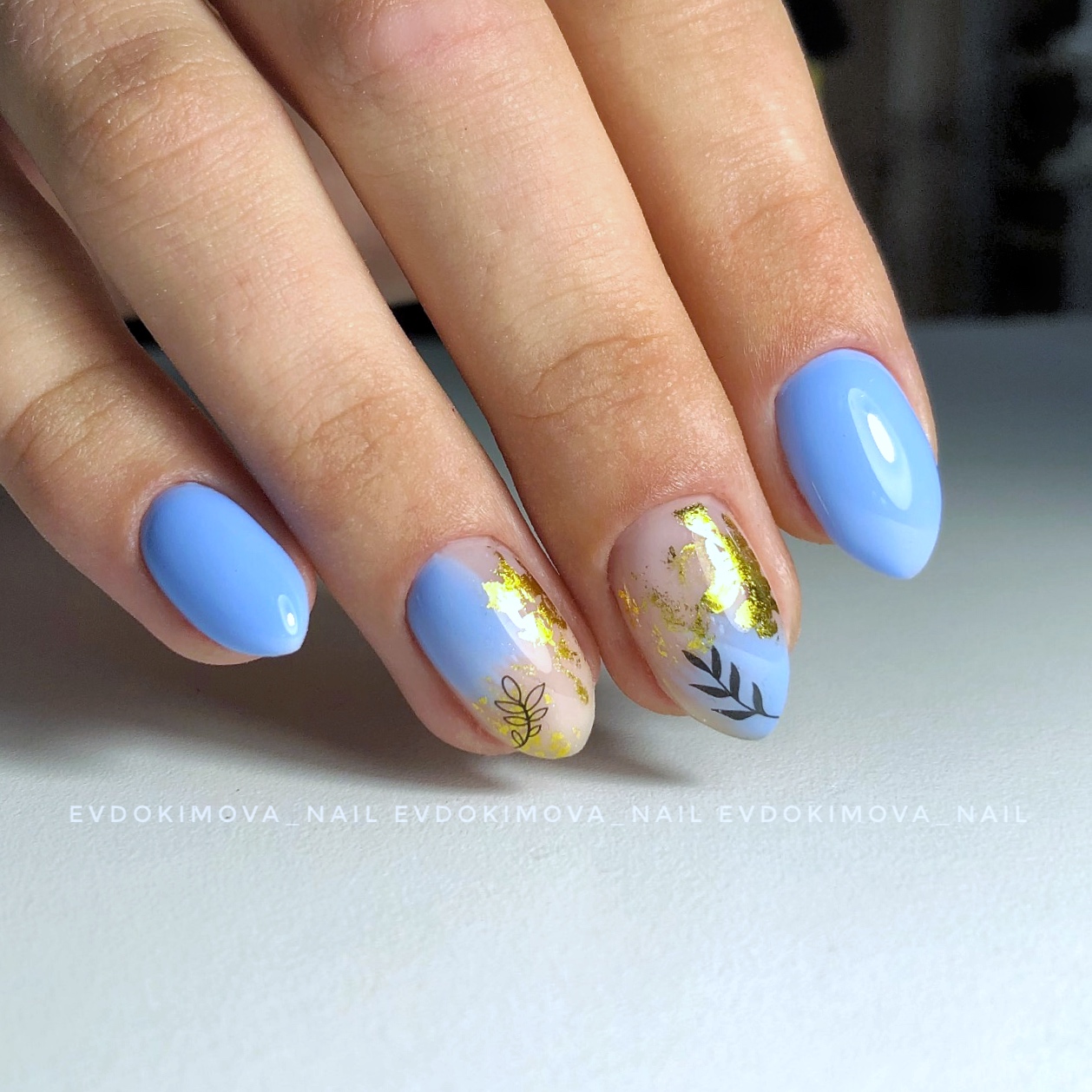 Маникюр с растительными слайдерами и золотой фольгой в голубом цвете на короткие ногти.