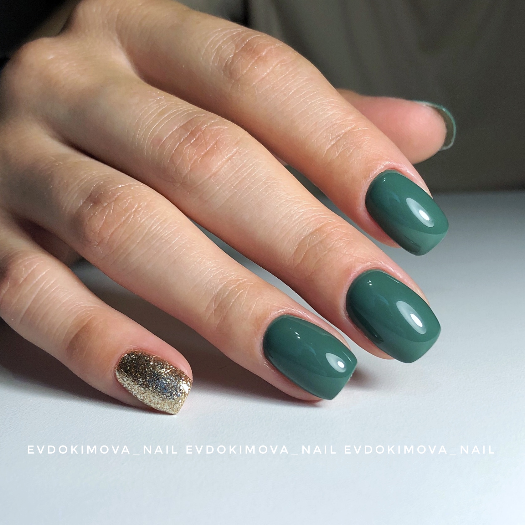 Маникюр с золотыми блестками в темно-зеленом цвете на короткие ногти.
