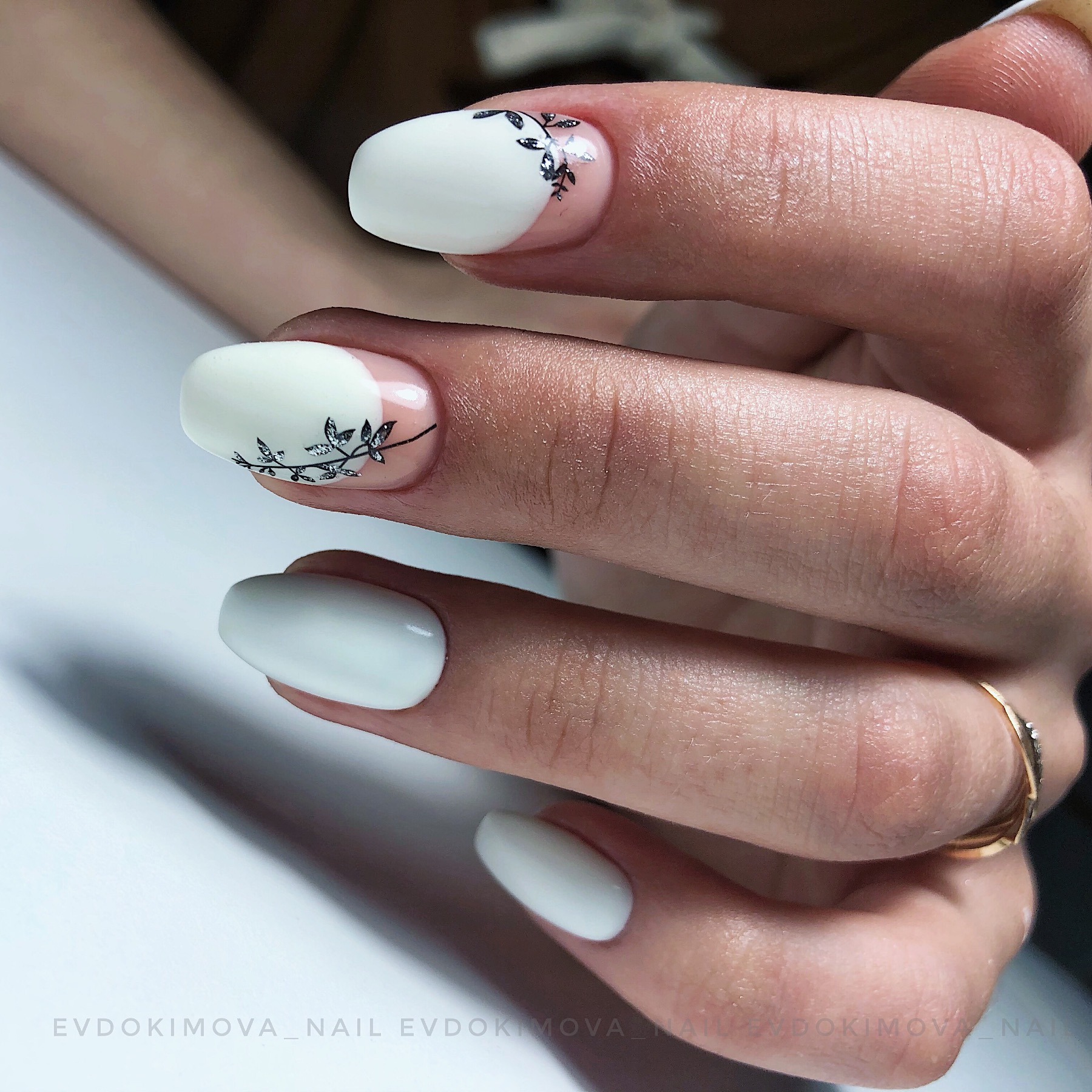 Маникюр с лунным дизайном и растительным рисунком в белом цвете на длинные ногти.
