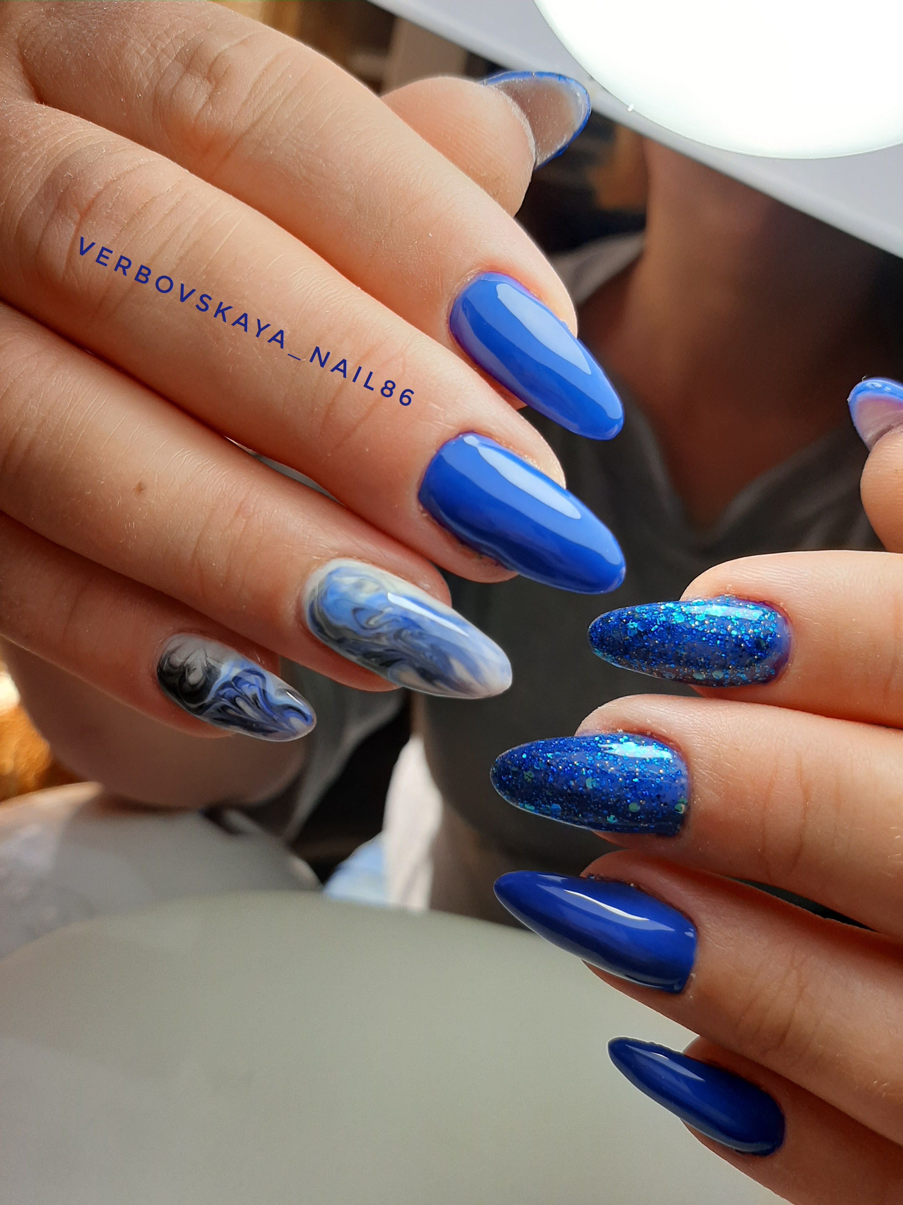 Маникюр с морским дизайном и блестками в синем цвете на длинные ногти.