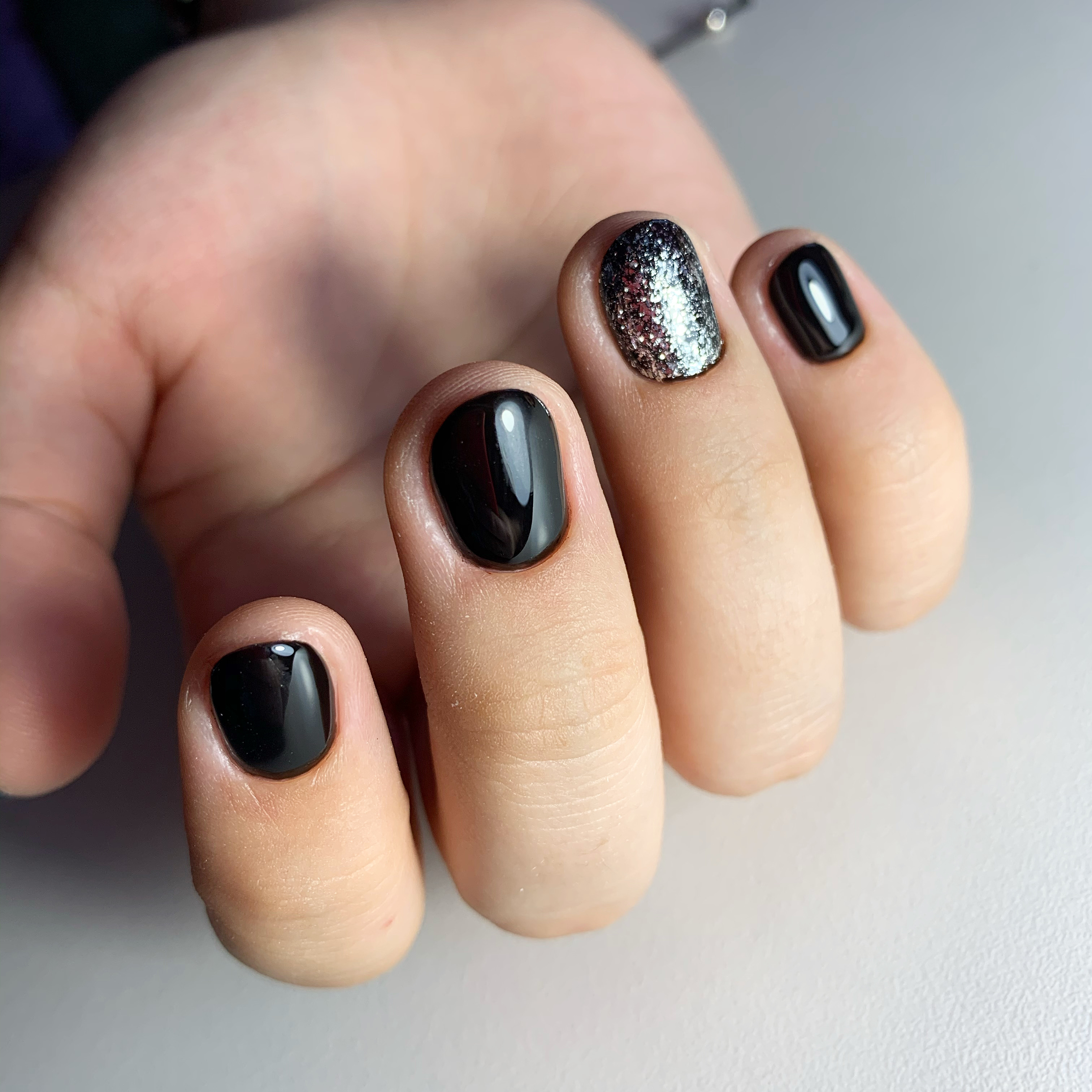 Маникюр с серебряными блестками в черном цвете на короткие ногти.