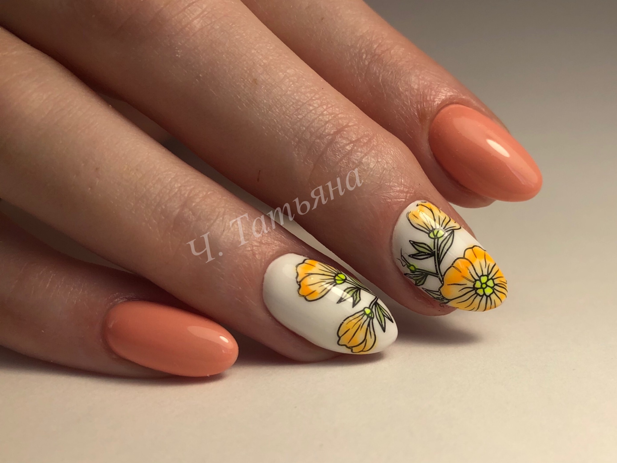 Маникюр в персиковом цвете с белым дизайном и цветочным рисунком.