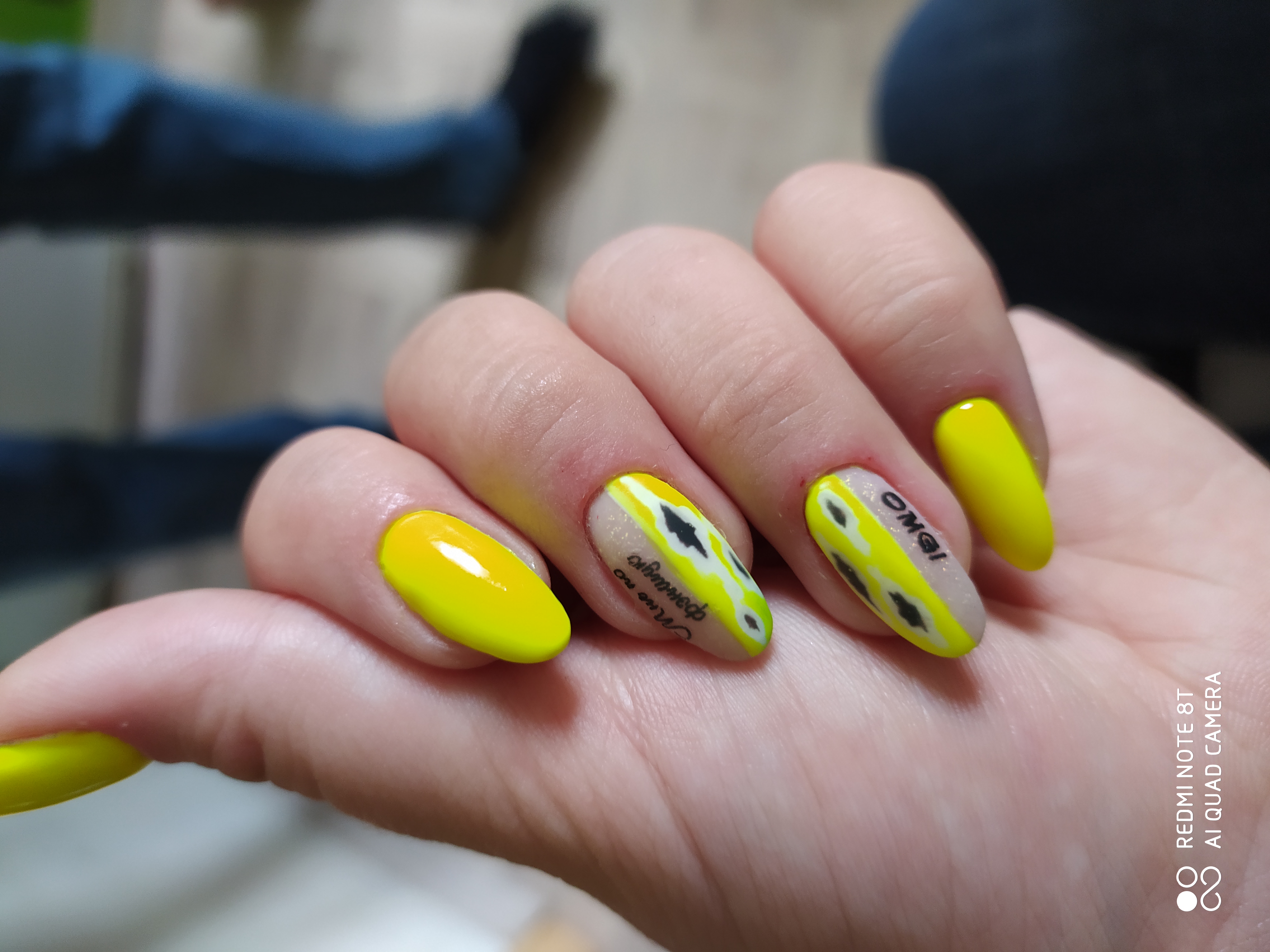 Маникюр с абстрактным рисунком и надписями в желтом цвете на длинные ногти.