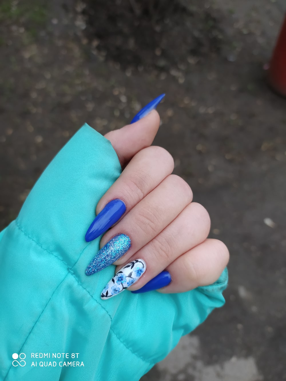 Маникюр с цветочным рисунком и блестками в синем цвете на длинные ногти.