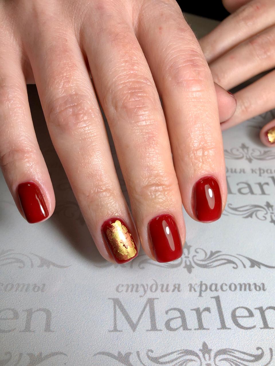 Маникюр с золотой фольгой в темно-красном цвете на короткие ногти.