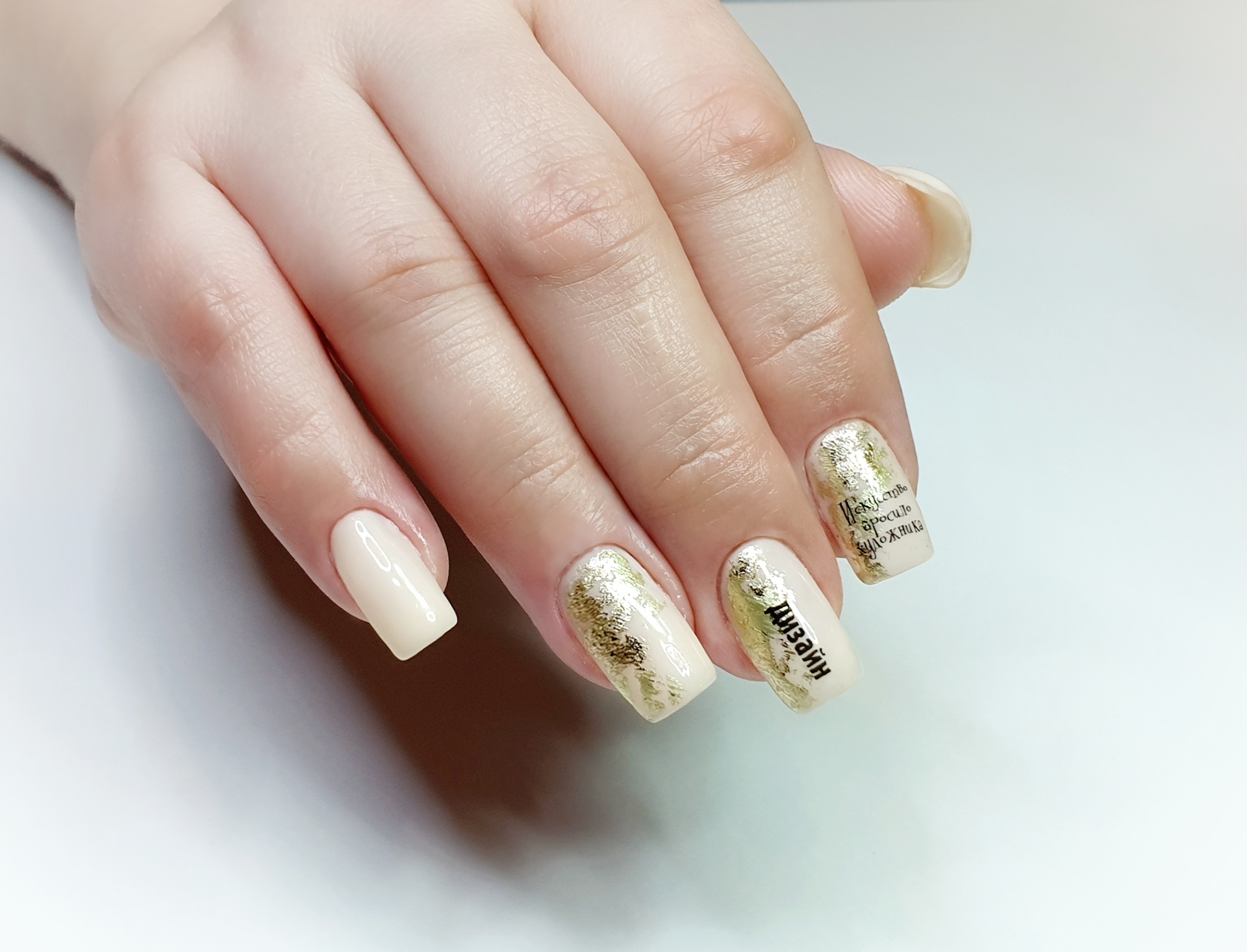 Маникюр с золотой фольгой и надписями в бежевом цвете на короткие ногти.