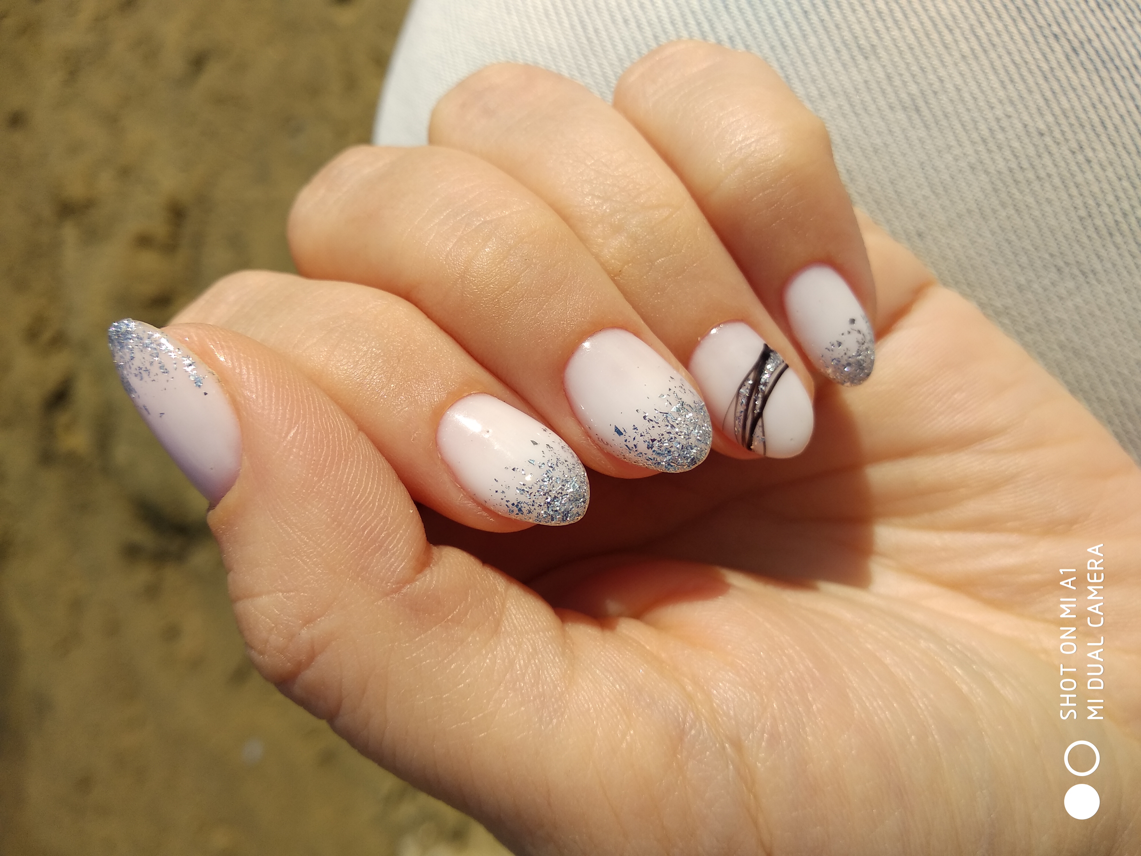Маникюр с серебряными блестками и паутинкой в молочном цвете на короткие ногти.