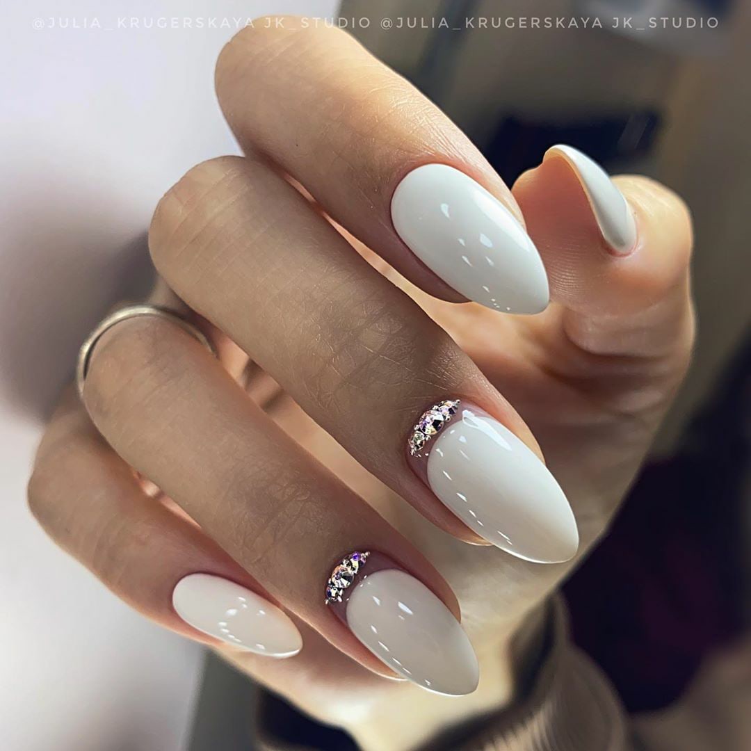 Маникюр с лунным дизайном и стразами в белом цвете на длинные ногти.