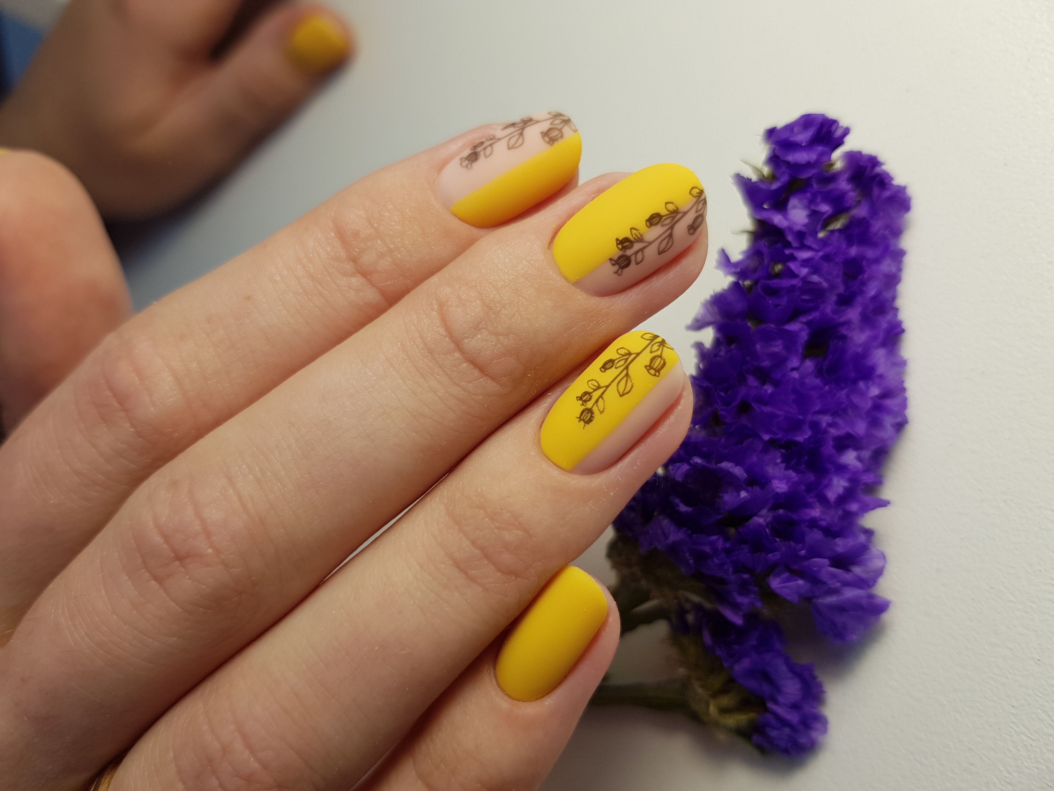 Матовый маникюр с растительными слайдерами в желтом цвете.