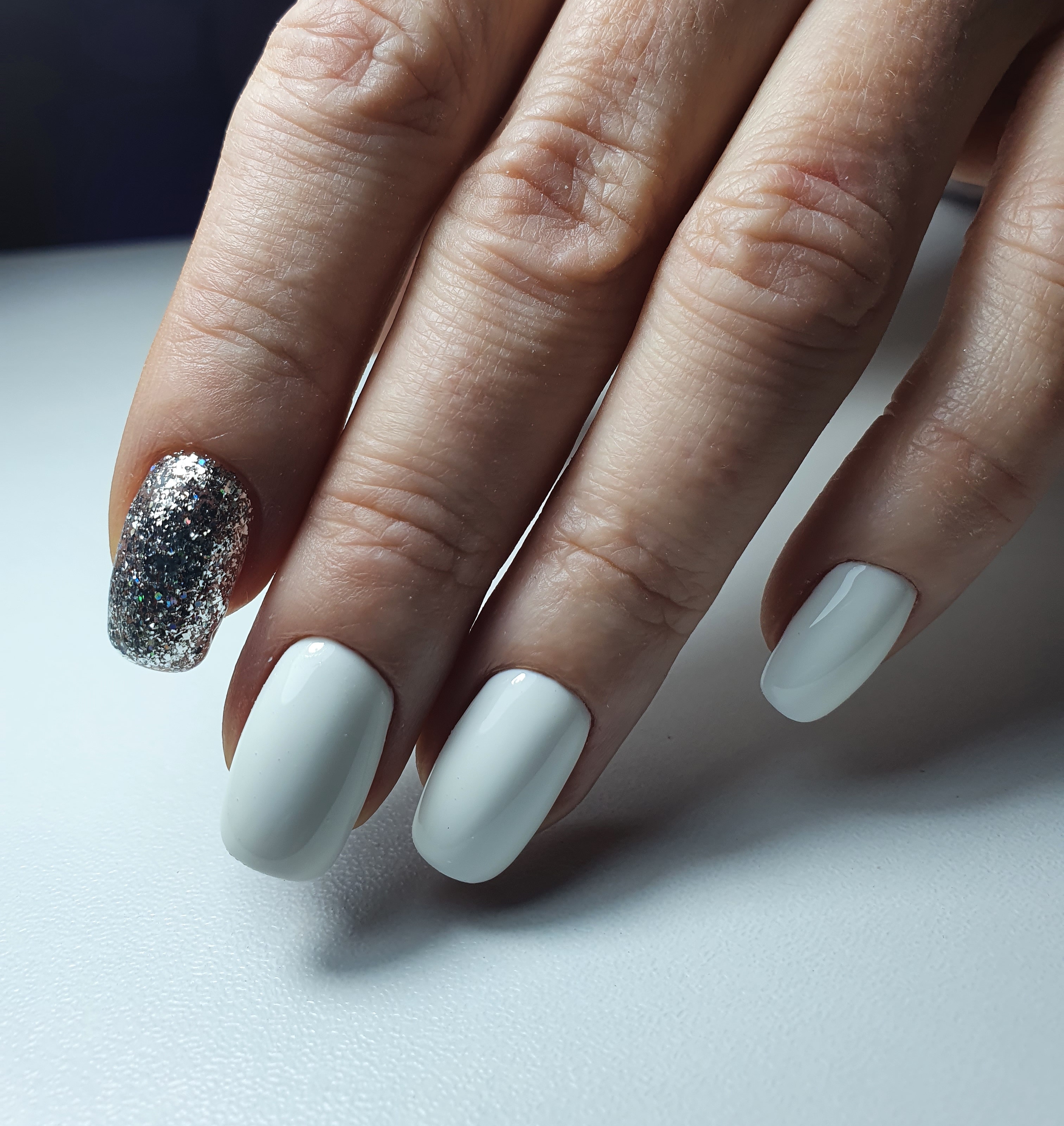 Маникюр с серебряными блестками в белом цвете на короткие ногти.