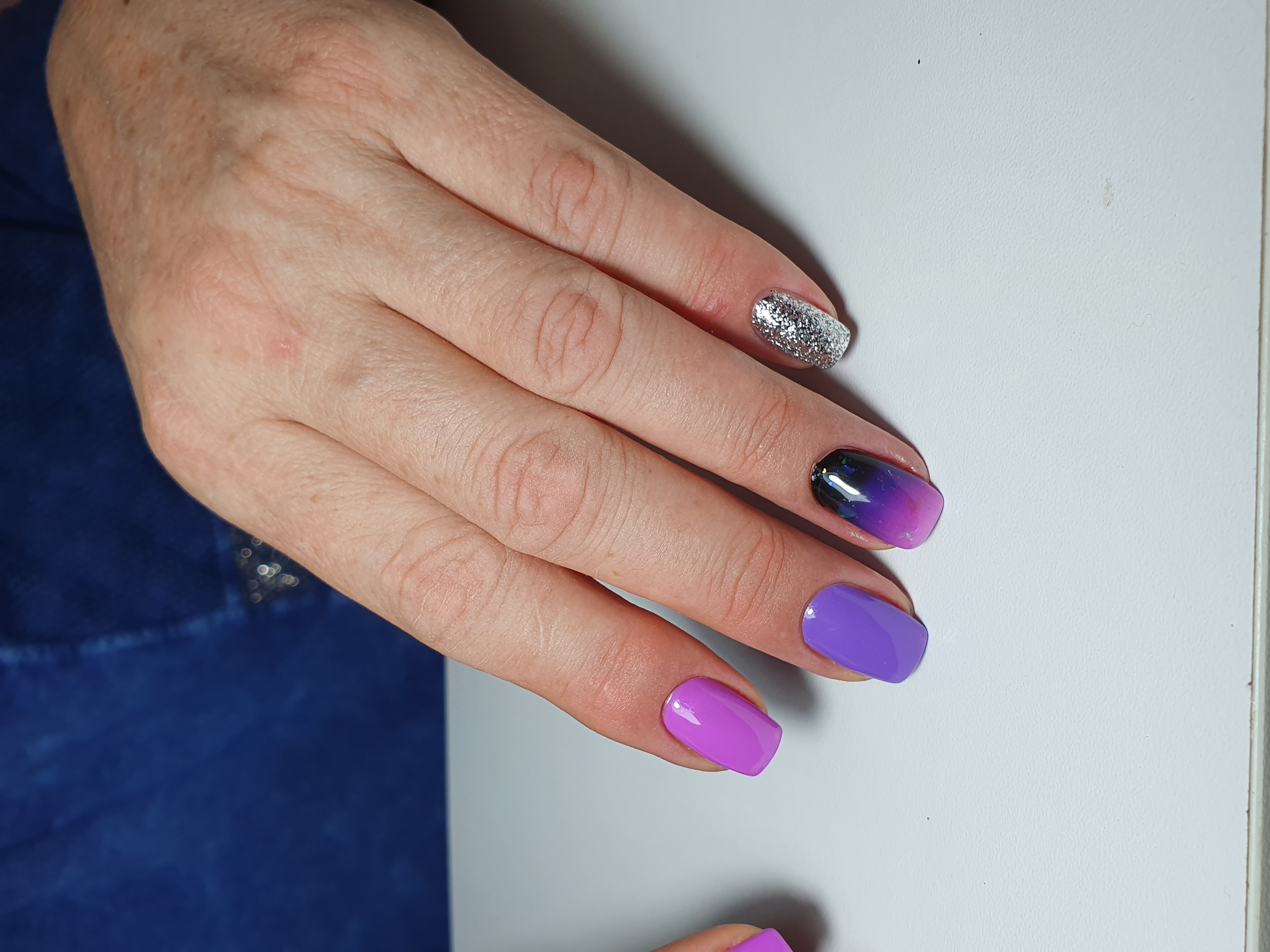 Маникюр с градиентом и серебряными блестками в фиолетовом цвете.