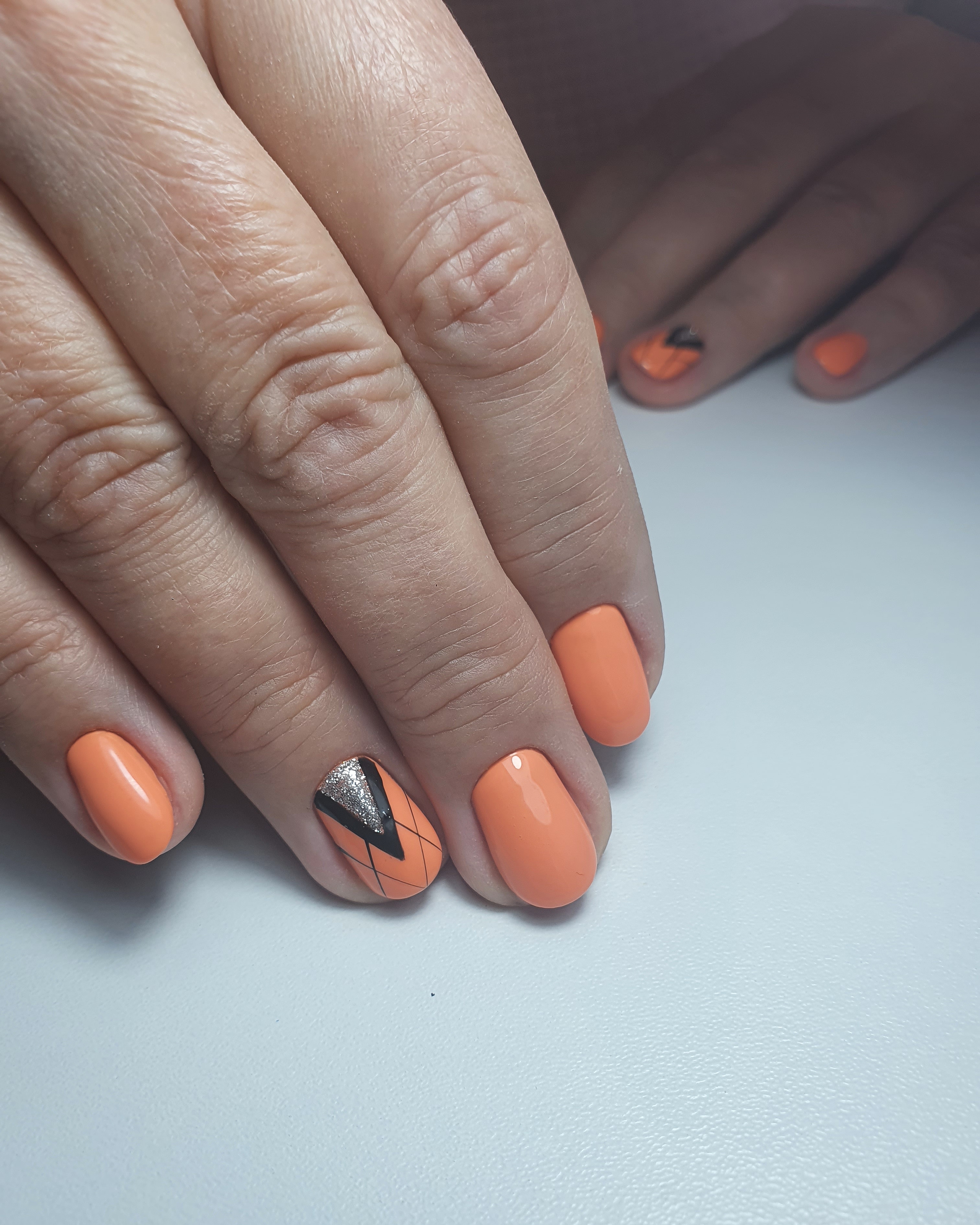 Геометрический маникюр с серебряными блестками в оранжевом цвете на короткие ногти.