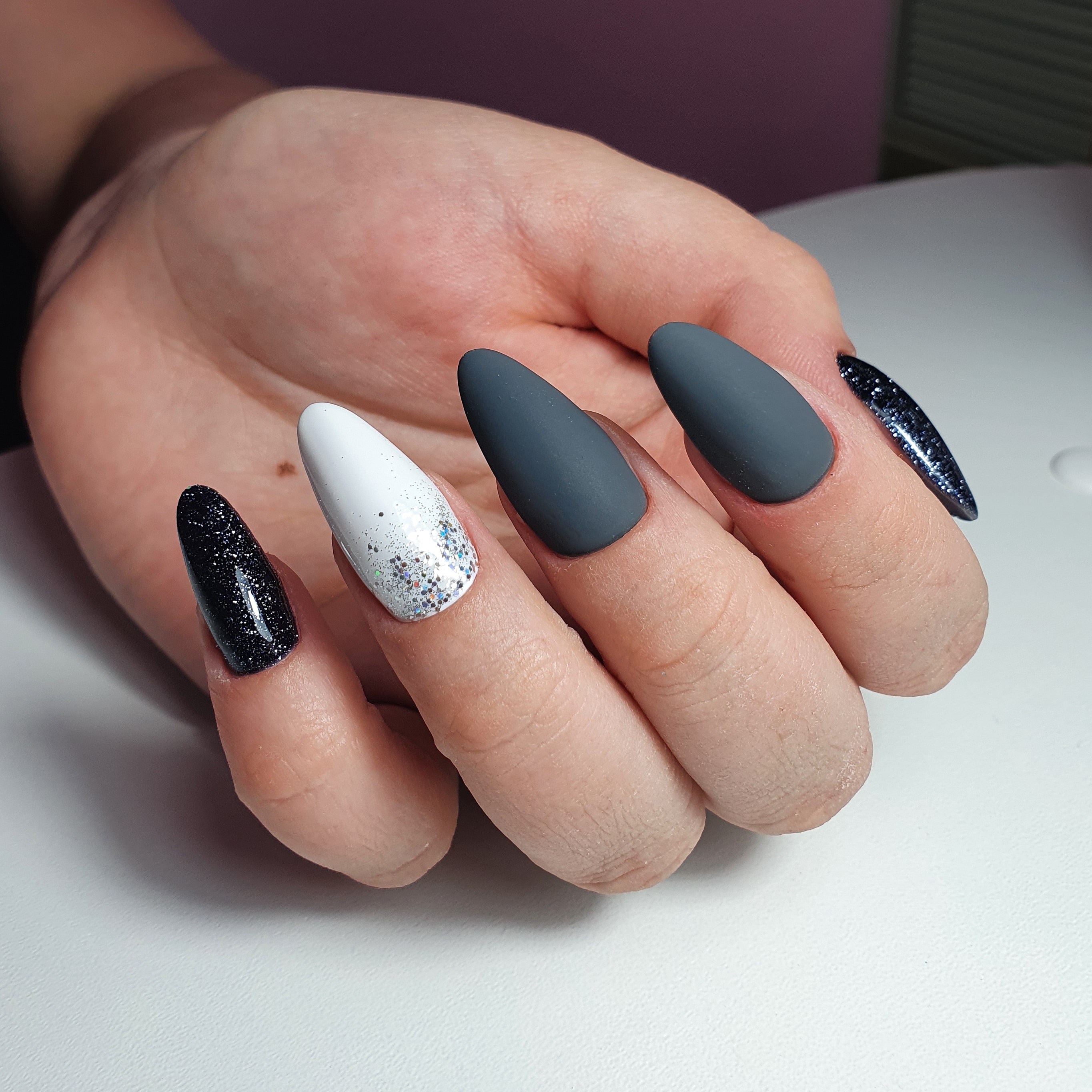Маникюр с блестками и матовым дизайном в черном цвете на длинные ногти.