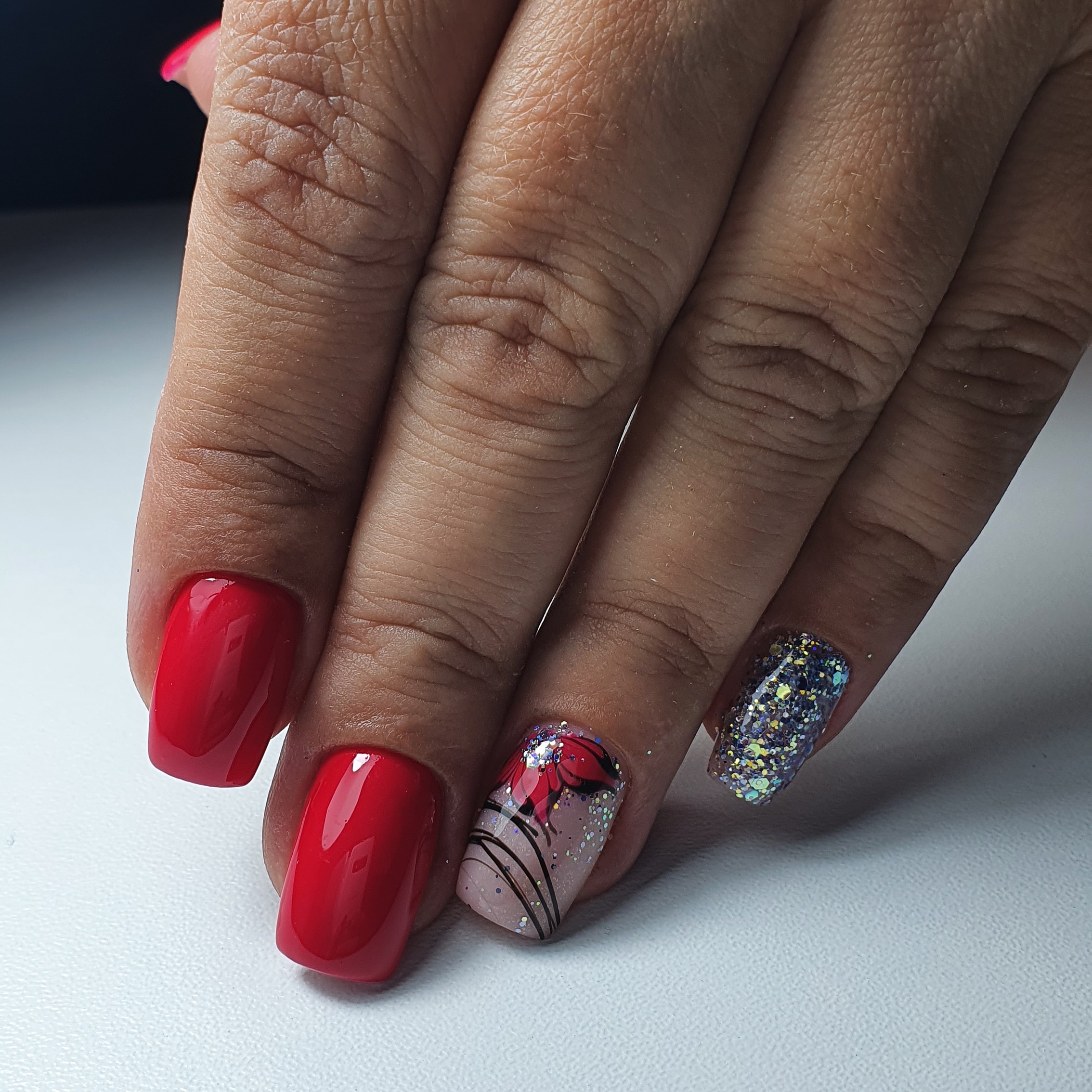 Маникюр с цветочным рисунком, серебряными блёстками и паутинкой в красном цвете на короткие ногти.