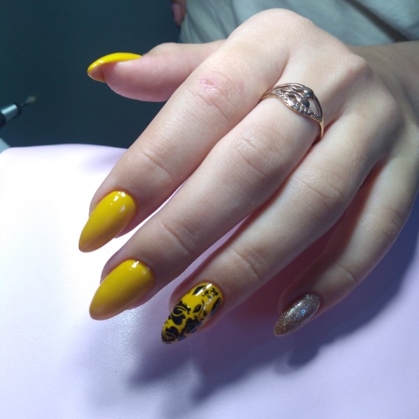 Маникюр с цветочным рисунком и золотыми блестками в желтом цвете на длинные ногти.