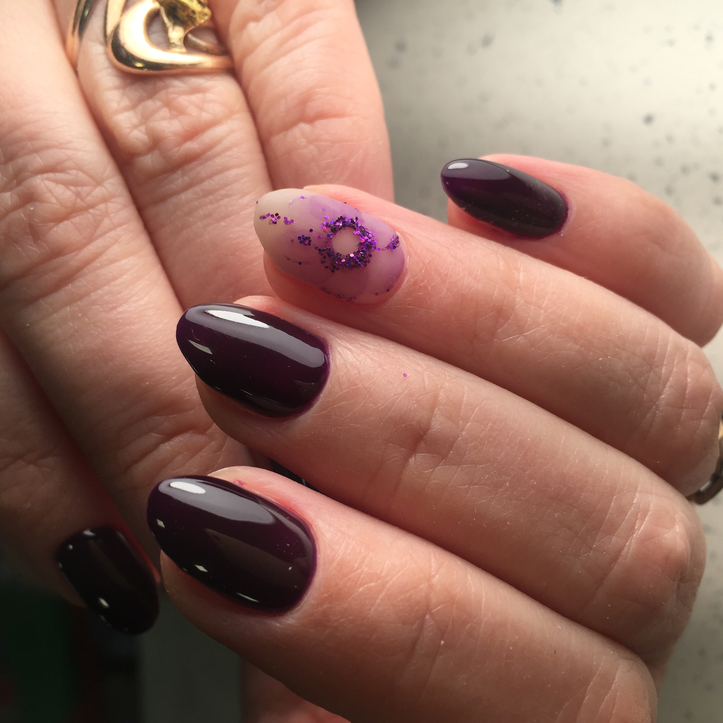 Маникюр в тёмном баклажановом цвете с нюдовым акварельным цветочным дизайном и фиолетовыми блёстками.