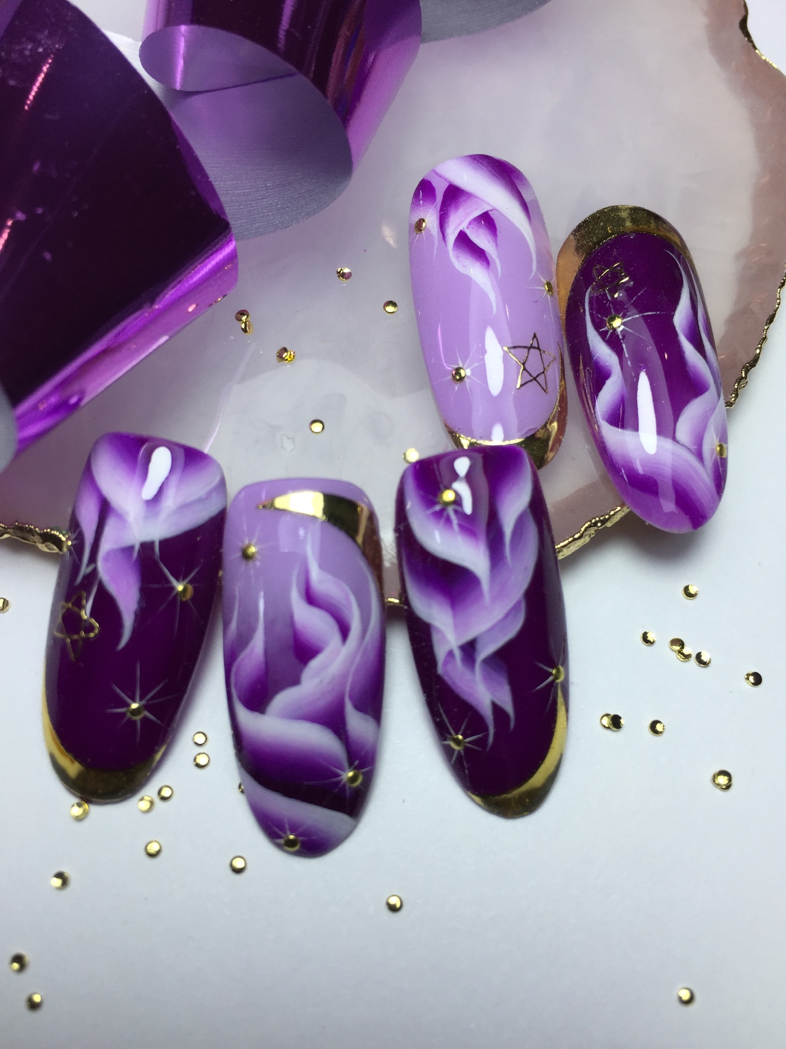 Маникюр в фиолетовом цвете с сиреневым абстрактным рисунком и золотыми полосками.