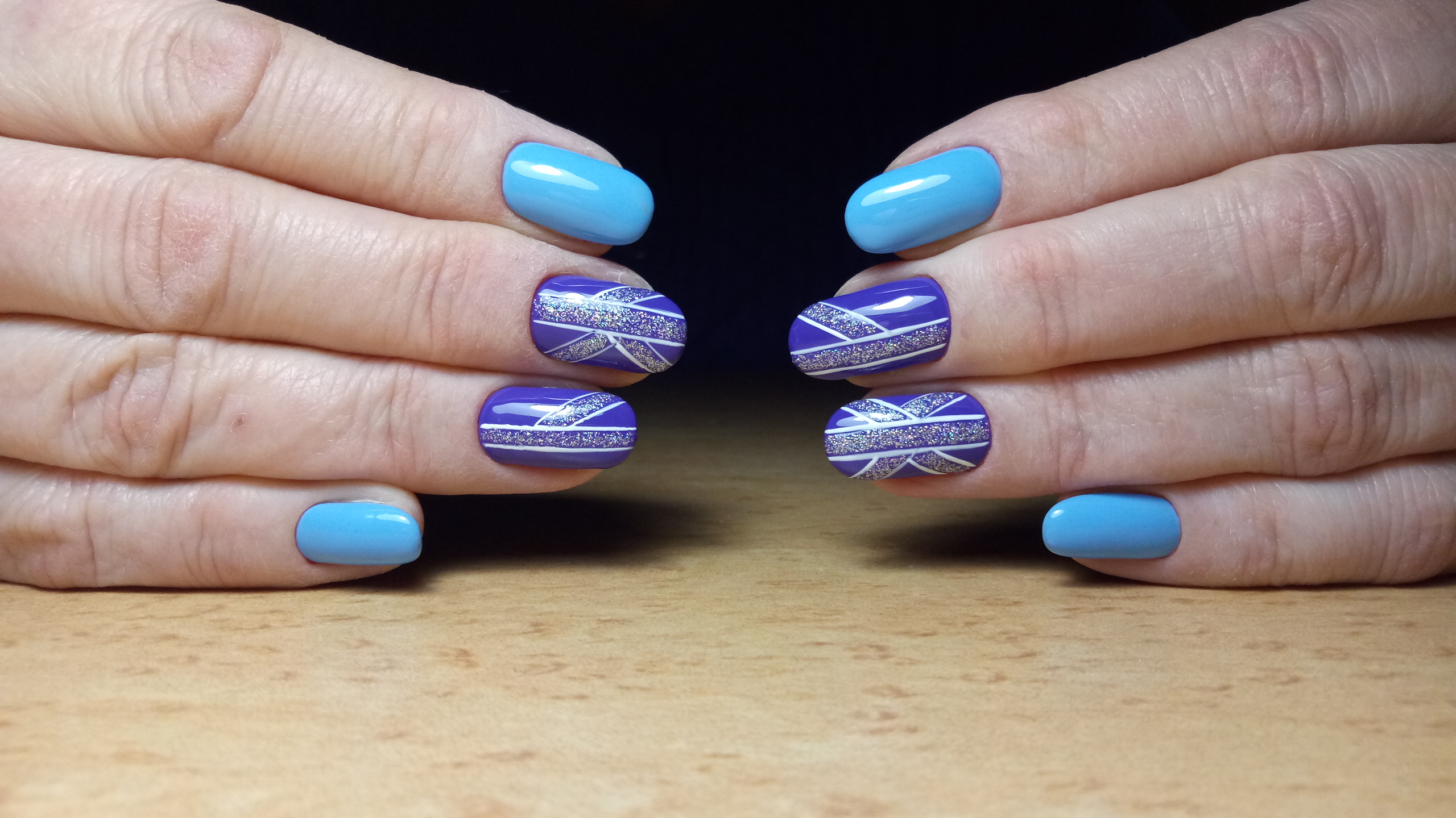 Маникюр в голубом цвете с фиолетовым дизайном, геометрическим рисунком и блёстками.