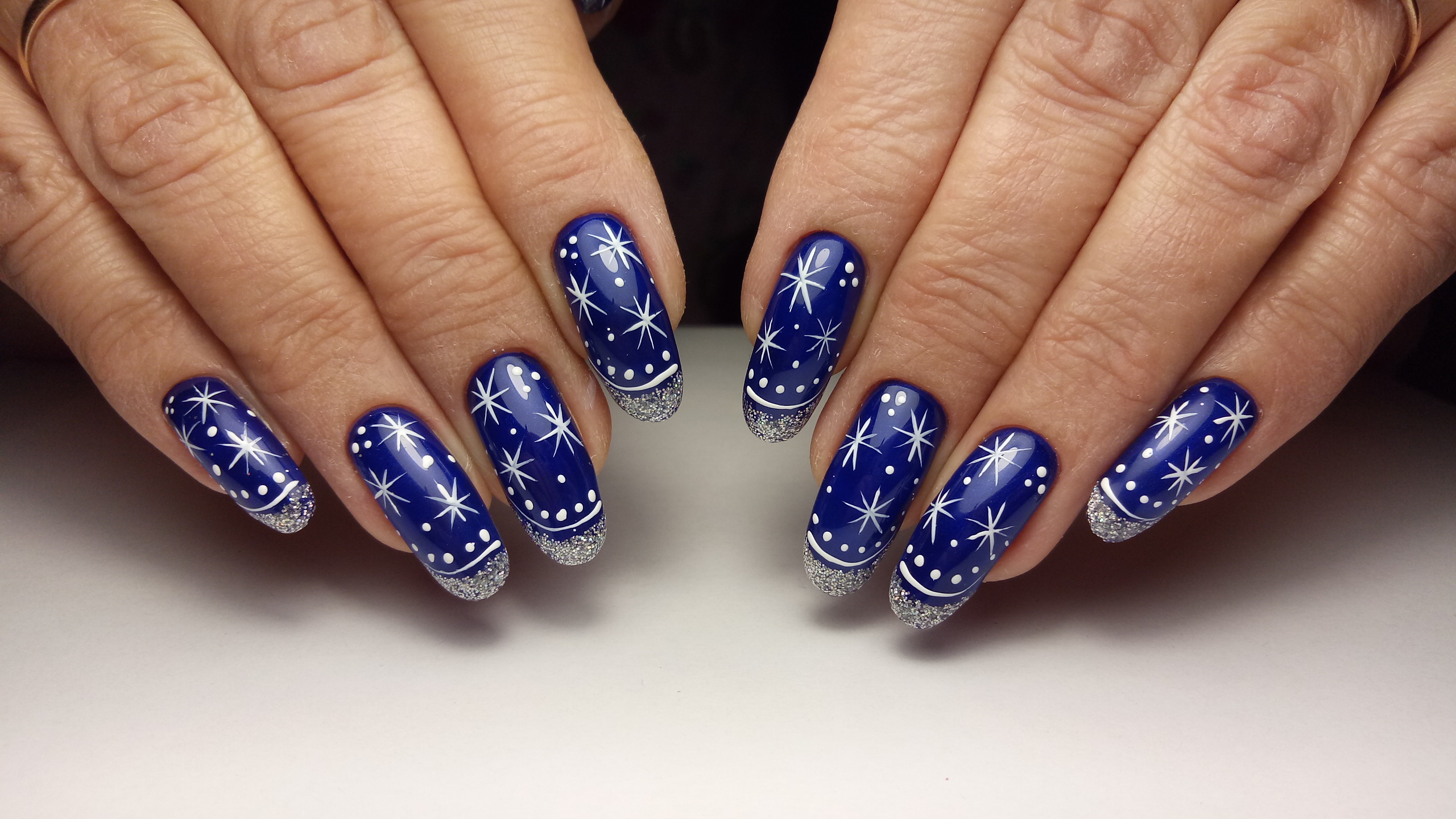 Маникюр в синем цвете с рисунком "снежинки" и серебряными блёстками.