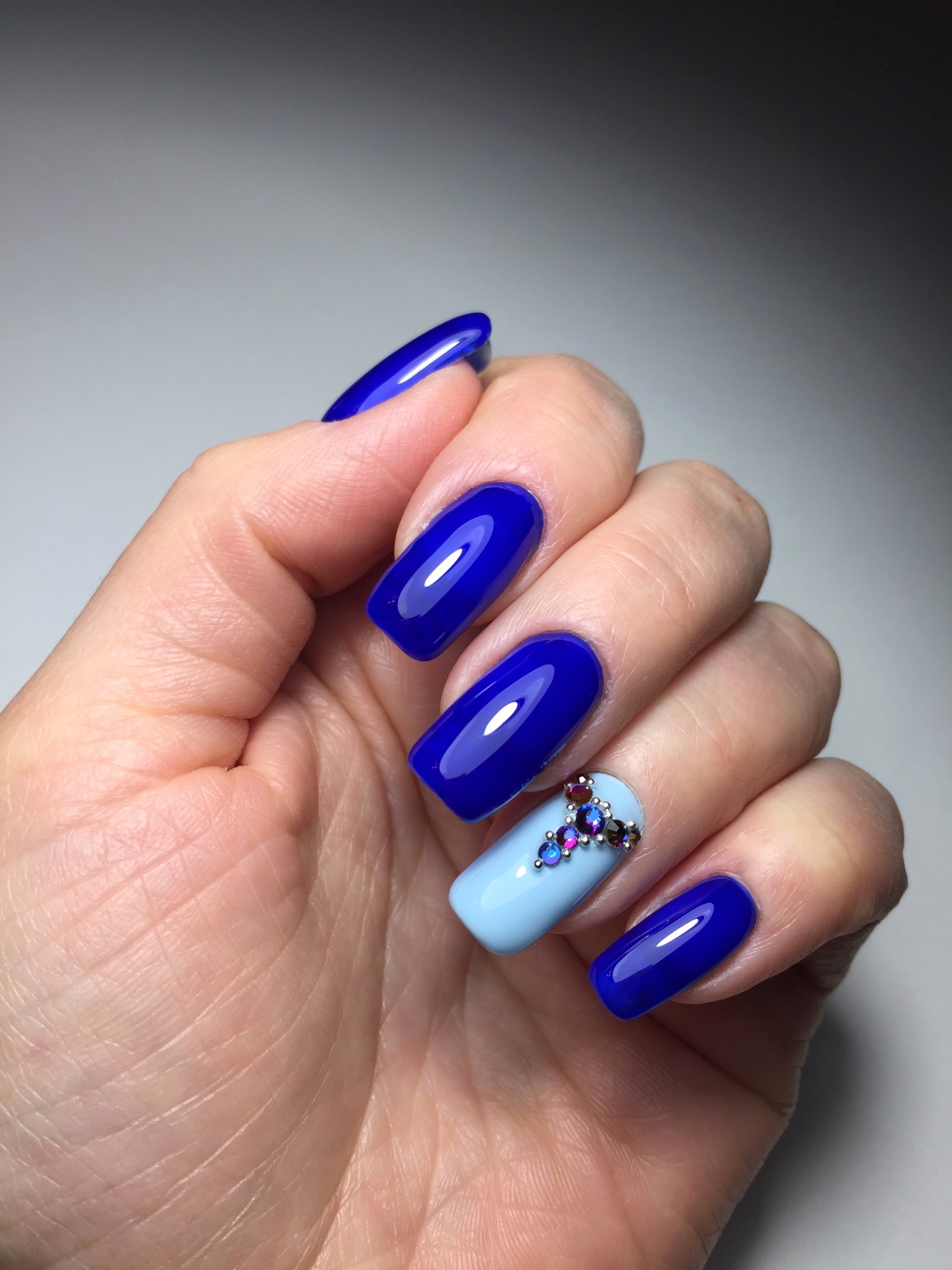 Маникюр в синем цвете с голубым дизайном и стразами.