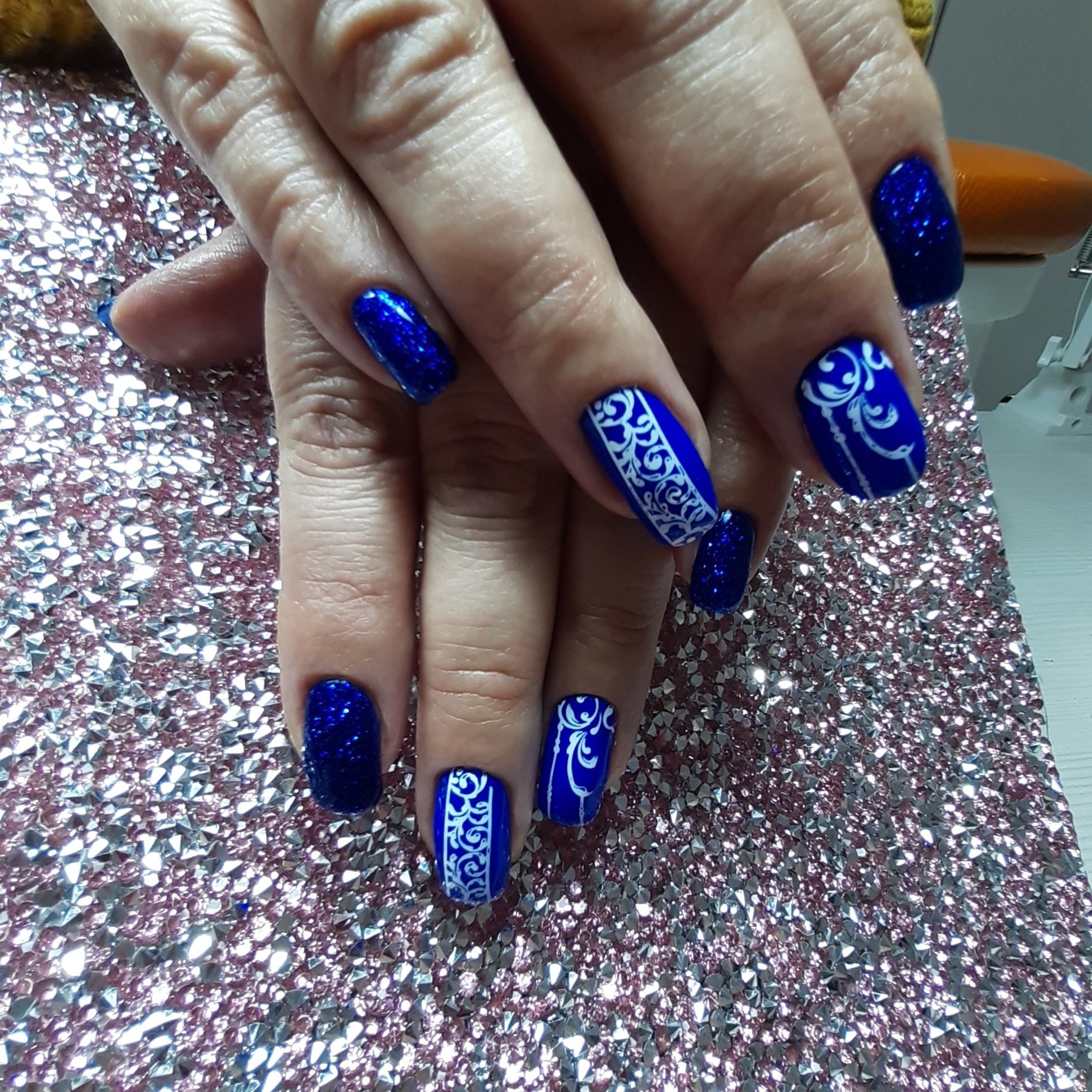 Маникюр с вензелями и блестками в синем цвете на короткие ногти.