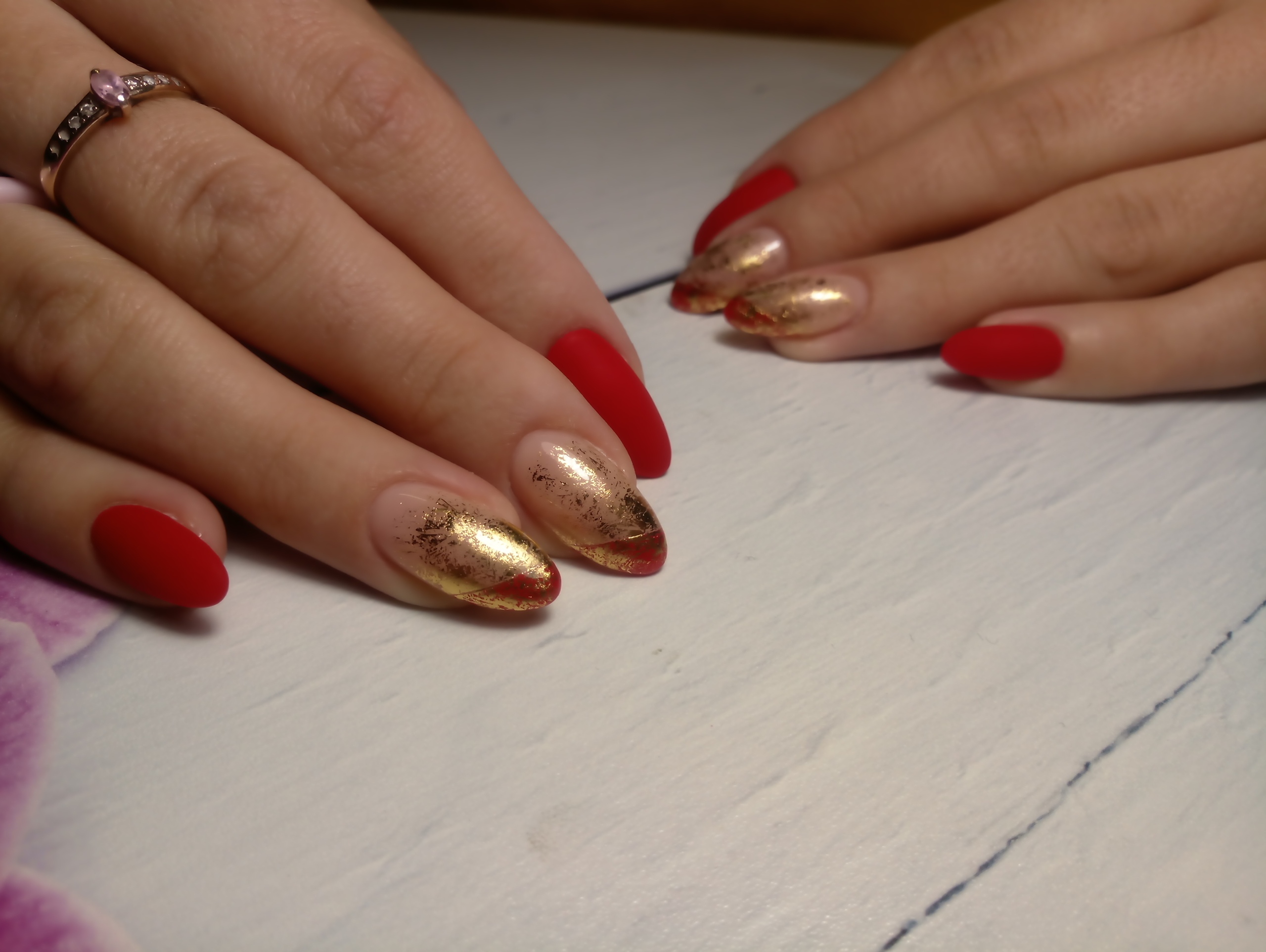 Матовый маникюр с золотыми блестками в красном цвете.