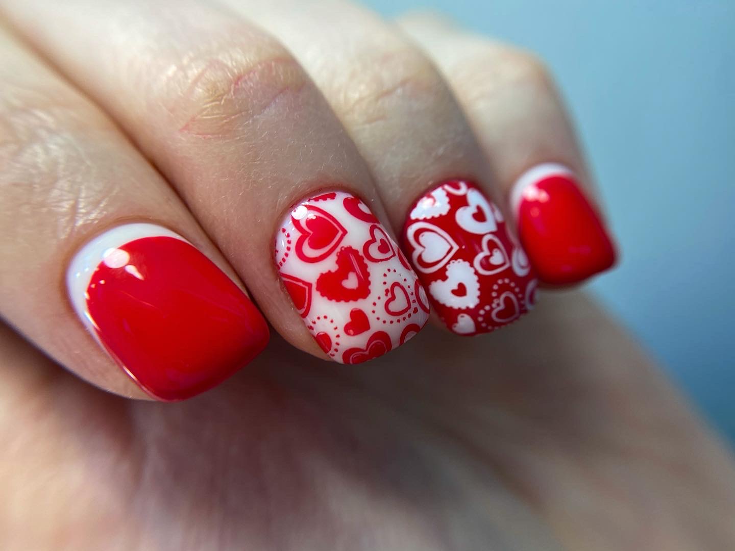 Лунный маникюр с сердечками в красном цвете на короткие ногти.