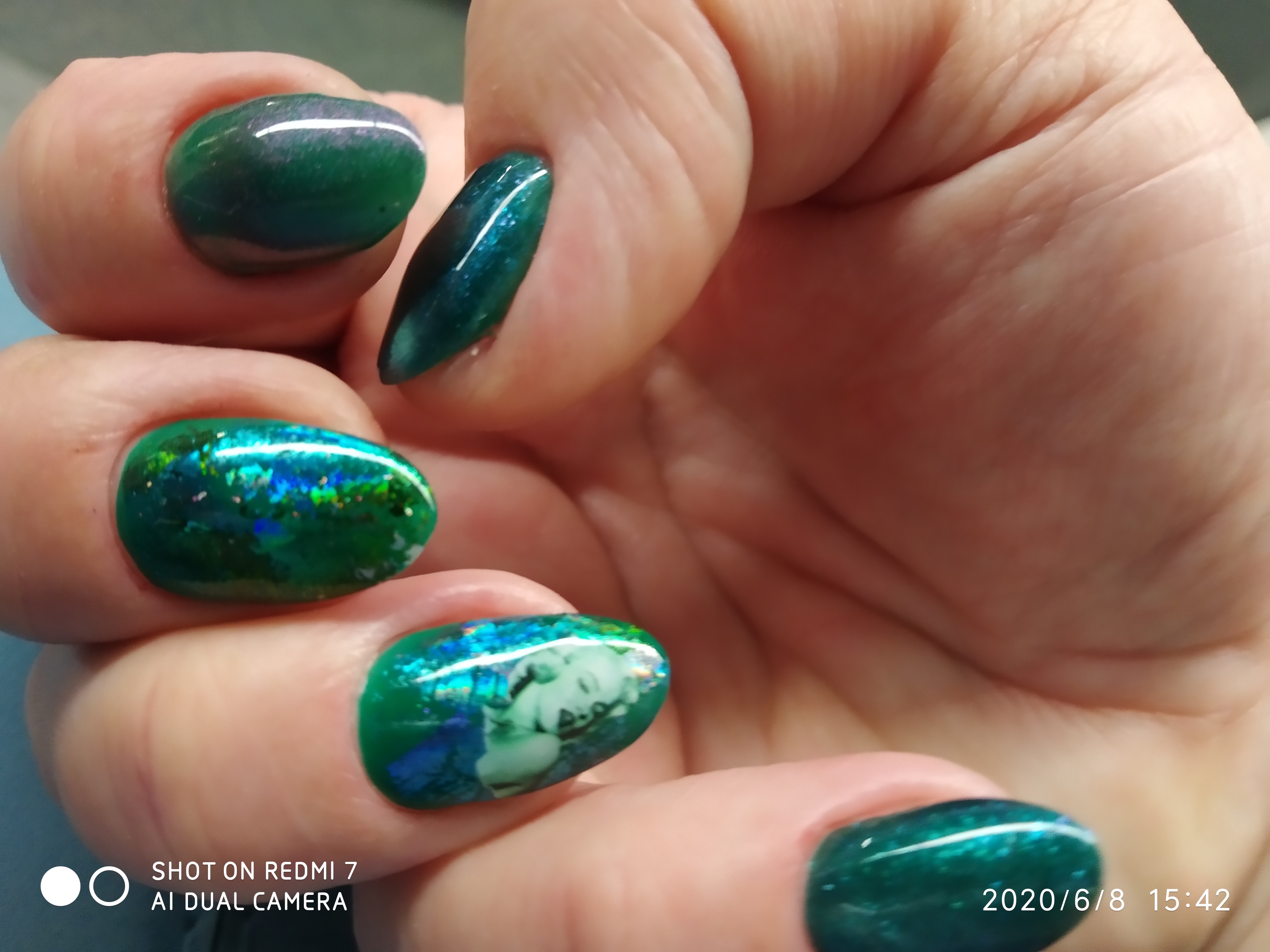 Маникюр с цветной фольгой и блестками в темно-зеленом цвете на короткие ногти.