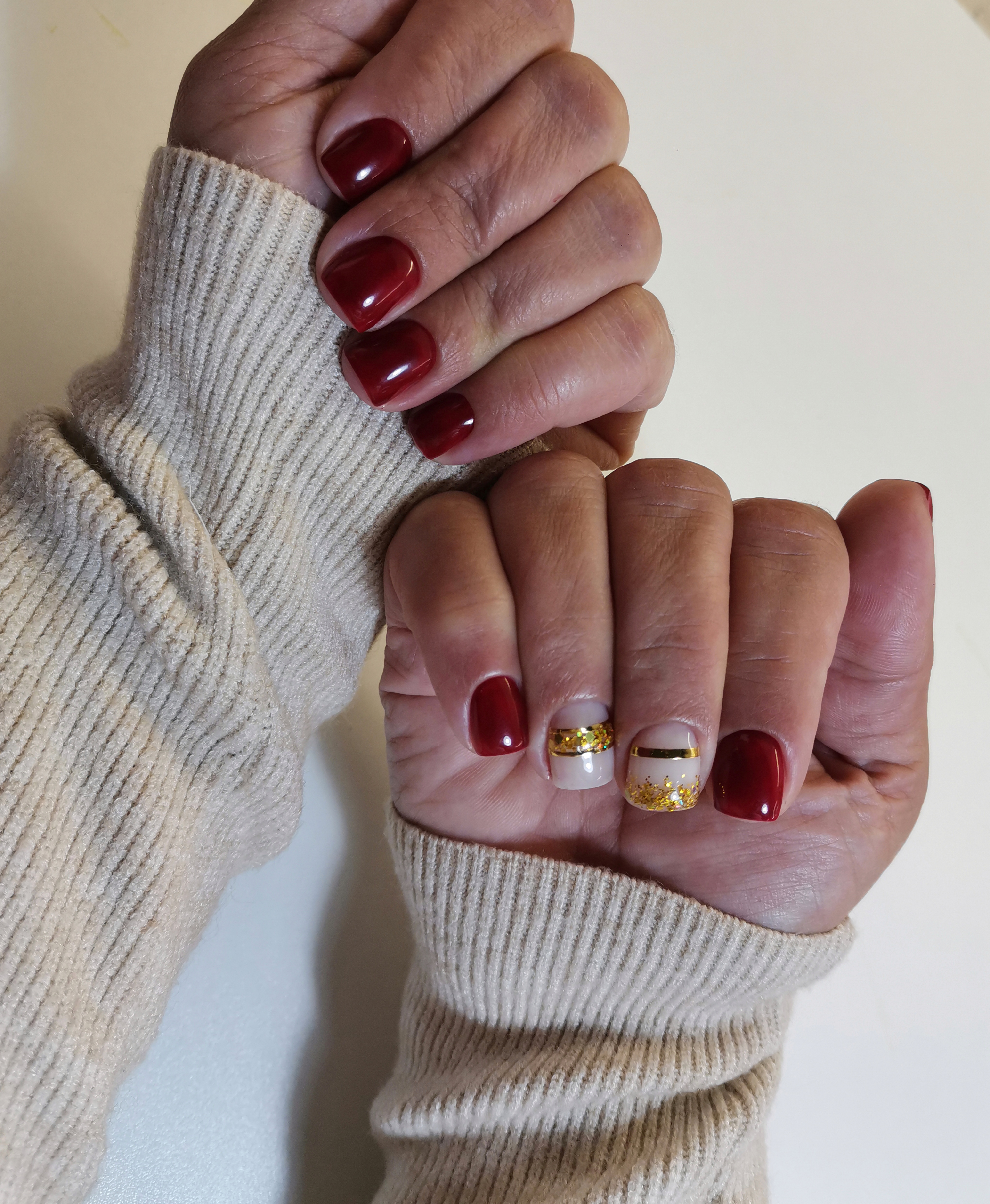 Маникюр с золотыми полосками и блестками в темно-красном цвете на короткие ногти.