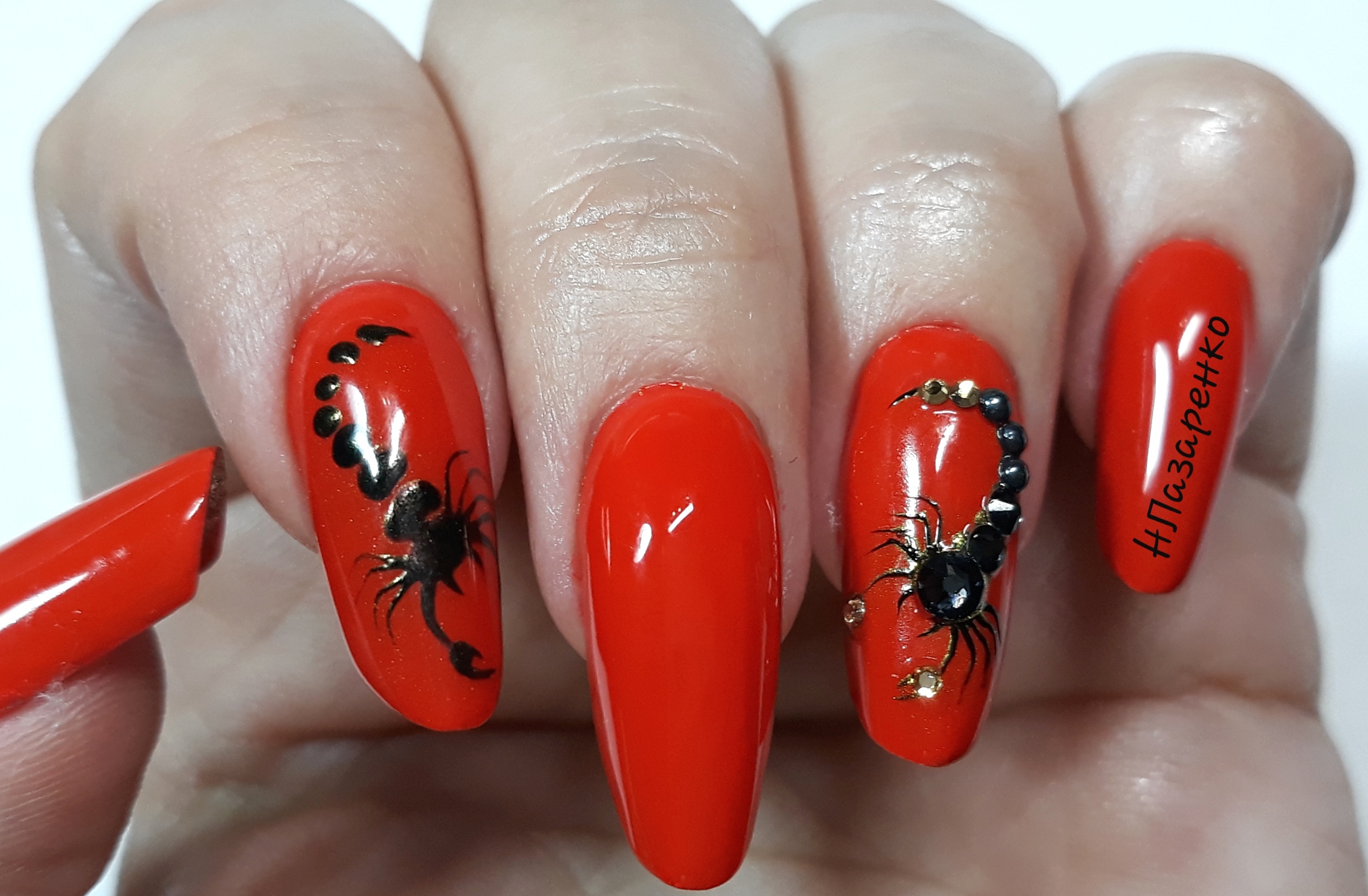 Маникюр со скорпионом и стразами в красном цвете на длинные ногти.
